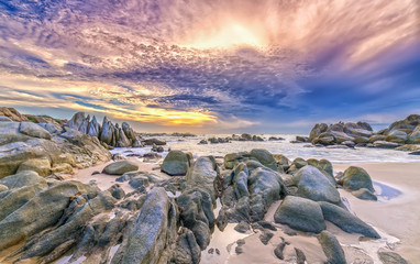 Dawn on the beach with brightly colored clouds, beneath a rock with beautiful shapes create beautiful scenery welcome bright day fresh