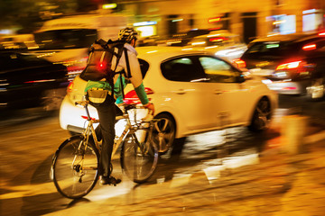 bicycle messenger in city traffic at night