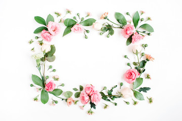 Fototapeta premium Round frame made of pink and beige roses, green leaves, branches on white background. Flat lay, top view. Valentine's background