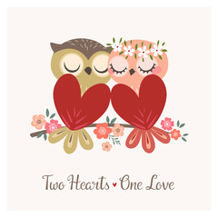 Fototapeta premium Greeting card with two cute owls in love sitting on flower branch for Valentine's day or wedding congratulations.