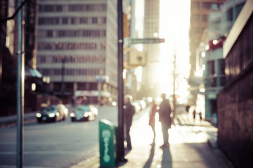 Obraz premium Niewyraźne ludzie chodzą po ulicy Vancouver o zachodzie słońca