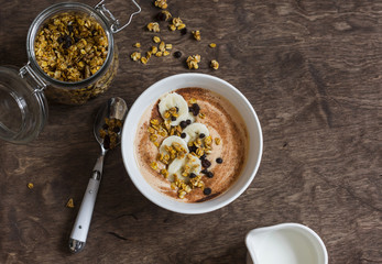 Pumpkin smoothie bowl with banana and granola on wooden table, top view. Delicious healthy breakfast