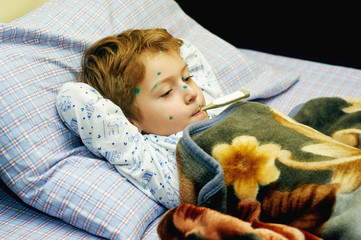 Sick child boy lying in bed with chicken pox