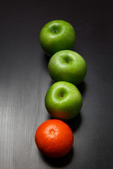 Fresh whole orange tangerine and apples on black background