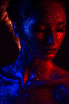 Art make up.Woman portrait with creative  make up, all face in blue and red tinsels, with shining sequins. perfect skin and lips. Concept of the magic effect on face