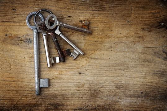 Bunch of different old keys on a rustic wooden board, background with copy space