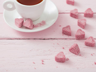 Granulated pink sugar  in the shape of heart and cup of tea  on