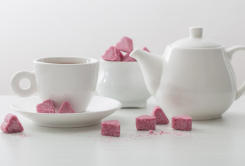 Granulated pink sugar  in the shape of heart and cup of tea  on