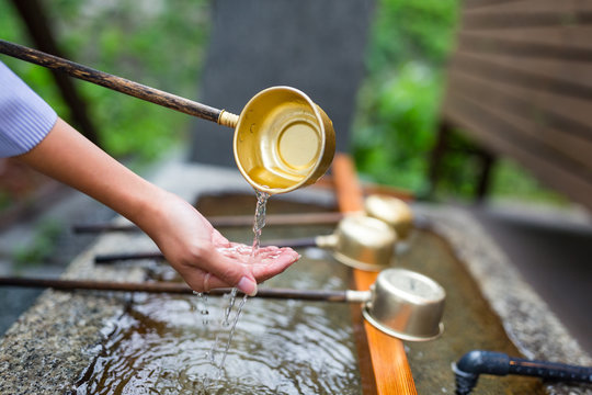 Woman washes her hand in fountain of Japanese temple
