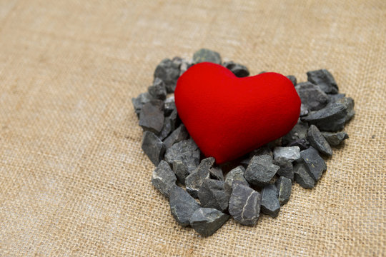Red heart on grey stone with space on hessian texture background