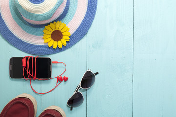 Top view of smartphone, red earphone ,sunglasses and hat 