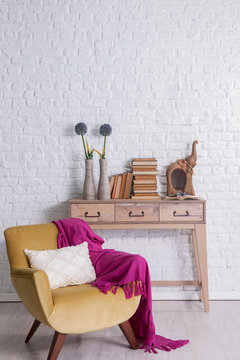 wooden table and dark yellow armchair with decorative brick wall concept