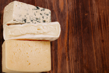 Delicious variety of cheese on old dark wooden table Top view 