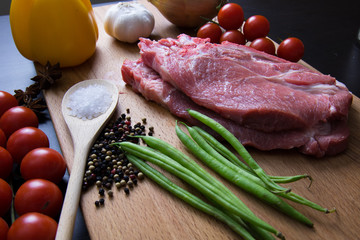 Fresh raw meat steak with spice and vegetables on wood surface