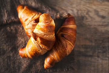Golden fresh croissants  on old wooden background close up with
