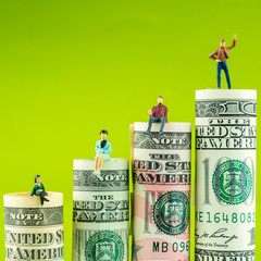 rising steps made of rolls of four most valued american dollar banknotes in one row on green...