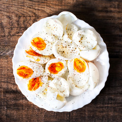 Hard boiled eggs, sliced in halves with black pepper spice on wo