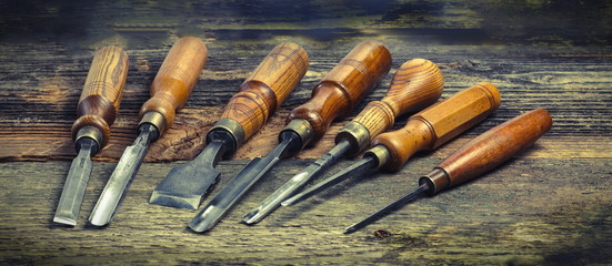 Old used wood lathe chisels selection on the wooden table - obrazy, fototapety, plakaty