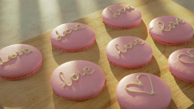 Pink macaroon - biscuits and modern dessert. Macaroon decorated with hearts and the words love for 14 February. Treats for the day of lovers. Bake on parchment paper