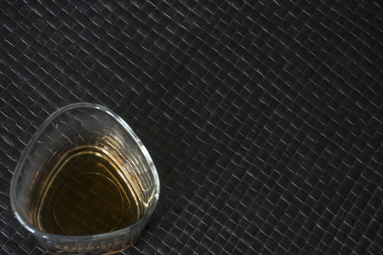 One glass of whiskey on black leather background