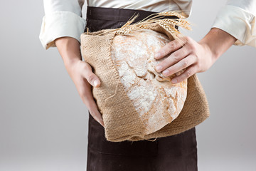 Baker man holding rustic organic loaf of bread in hands