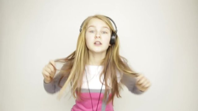 young girl listening music on headphones and funy dancing