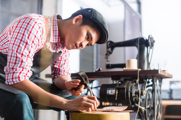 Asian shoe or belt maker in his leather workshop