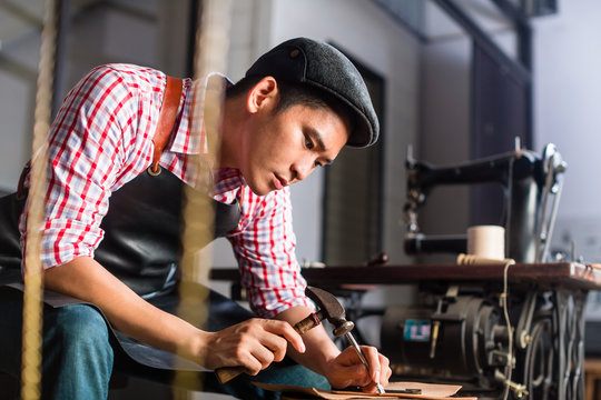 Asian shoe or belt maker in his leather workshop