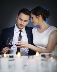 Couple clinking red wine glasses at table