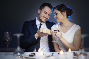 Young couple with present and glass of red wine.