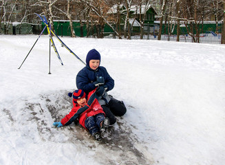 Happy children sliding from a little snowy hill.