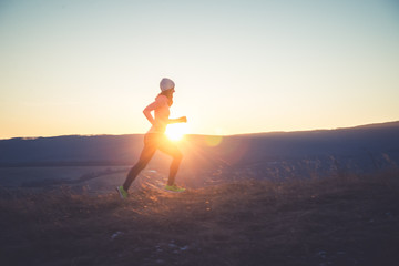 Runner girl on top of the hill in sunset