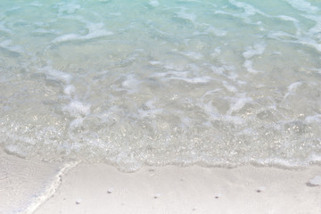 Fototapeta na wymiar Shallow azure seawater on the beach close up. Background