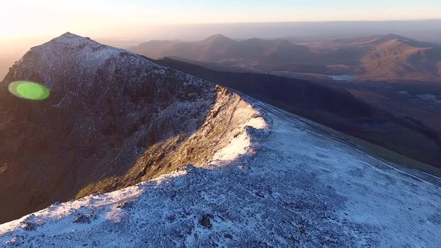 Spectacular panning aerial shot of sunrise over Crib Goch and Mount Snowdon.