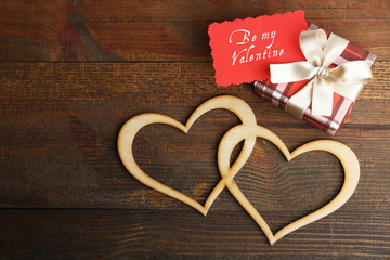 Gift box with decorative hearts on a wooden background. Inscription be my Valentine.