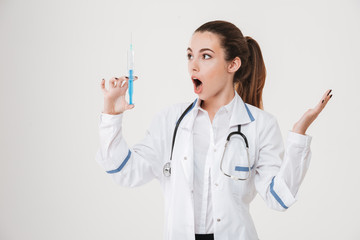 Portrait of amazed pretty young woman standing and holding syringe