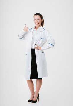 Full length of cheerful young woman doctor showing thumbs up