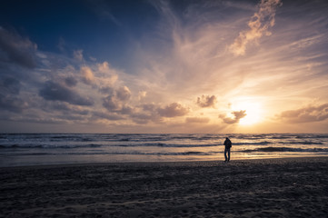 man walking on the sea shore at sunset