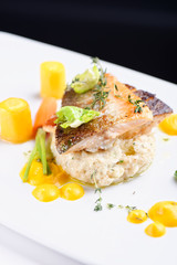 Fine dining, fish fillet breaded in herbs and spice on vegetable risotto.