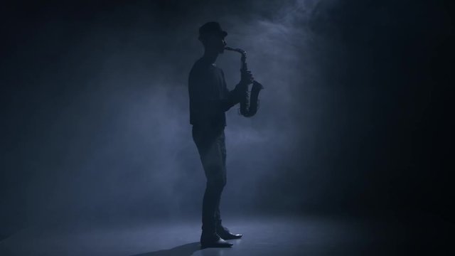 In a dark smoky studio man playing the saxophone