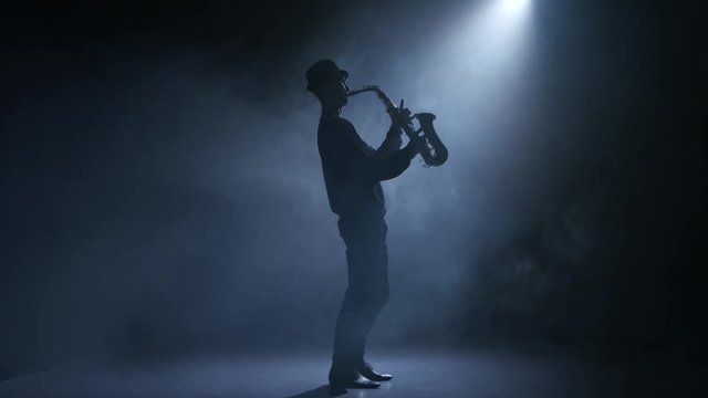 In the spotlight musician man playing the saxophone. Smoky studio