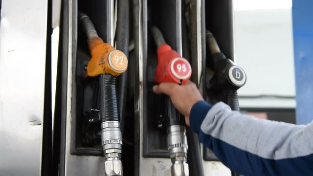 Man fixing fueling nozzle on its place at petrol station