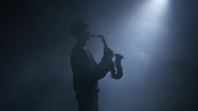 Saxophone. Man musician playing an instrument in a smoky studio