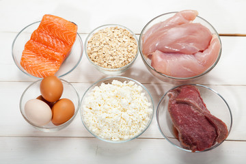 Proteins, fish, cheese, eggs, meat and chicken on a white wooden background