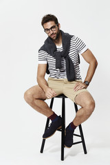 Man on stool wearing shorts and striped t-shirt, portrait
