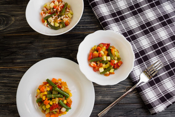 Vegetable salad in a white plate on a wooden background. Dietary dish.