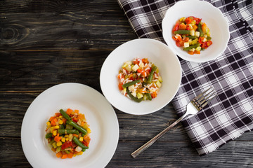 Vegetable salad in a white plate on a wooden background. Dietary dish.