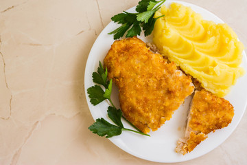Chicken breast in breadcrumbs with mashed potatoes on a white plate