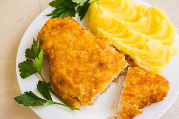 Chicken breast in breadcrumbs with mashed potatoes on a white plate