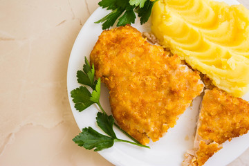 Chicken breast in breadcrumbs with mashed potatoes on a white plate